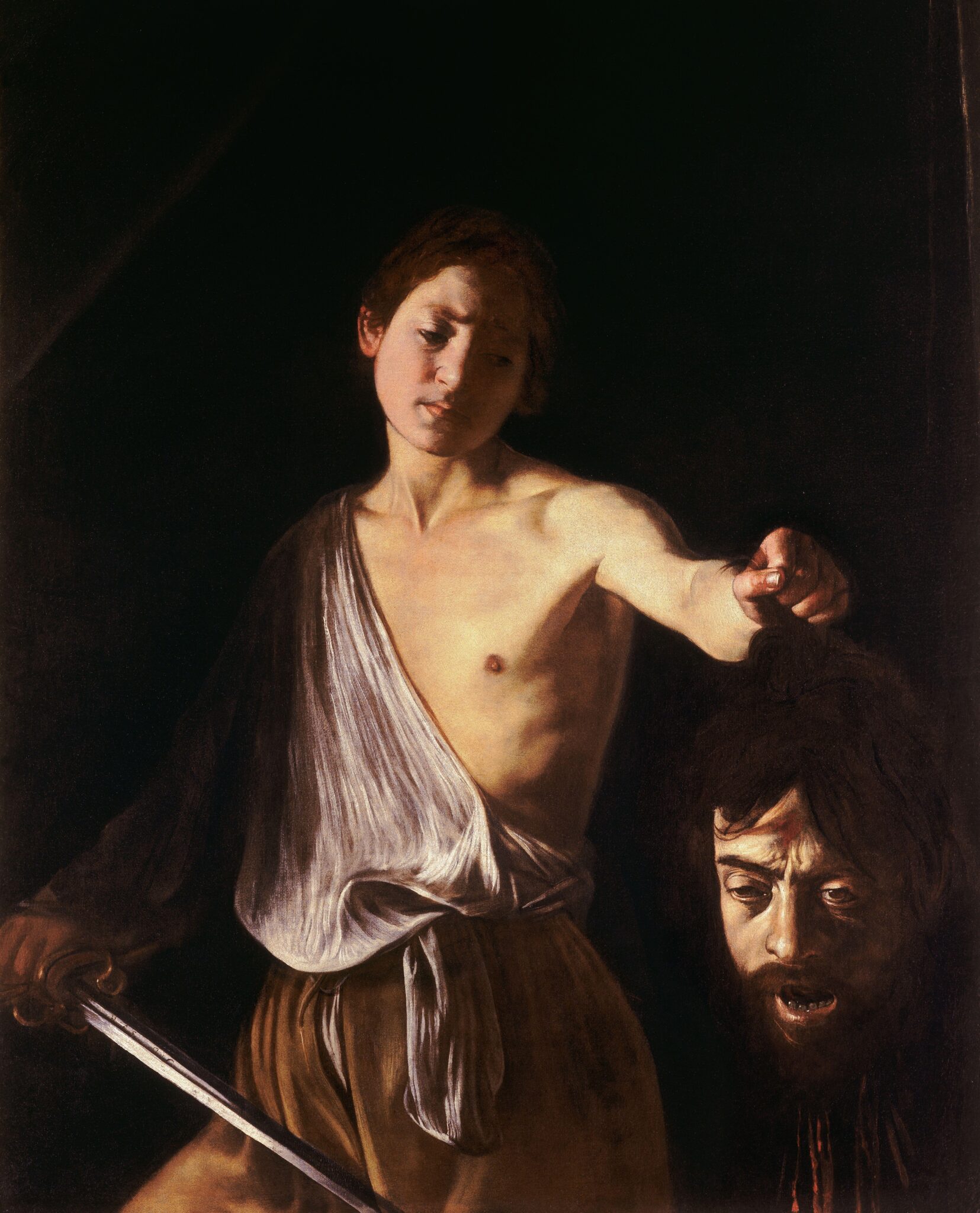 Caravaggio (Italy, 1571–1610) 
David with the Head of Goliath (c. 1609–1610). Oil on canvas, 200 x 100 cm (78.7 x 39.3 in). Galleria Borghese, Rome

The 17th-century Baroque painter Caravaggio seemed fascinated by the biblical episode of David and Goliath. He painted 3 versions. This is the last one, probably painted shortly before his death.

The future king of Israel, young David, presents King Saul with the head of the Philistine giant Goliath. He has just killed him with his slingshot, and holds in his hand the sword with which he decapitated him.

Goliath's head, which seems to spring from the shadows in Caravaggio's mastery of chiaroscuro, is deathly pale. The open mouth suggests terror, the blood drips from the decapitated head, but the open eyes convey dazedness and give the face a last semblance of life.

This head could be that of the painter himself. He has already painted himself as a sickly Bacchus. But this would be his last self-portrait, as a man defeated by divine justice.

And for good reason, Caravaggio had been facing death for several years. Condemned for the murder of Ranuccio Tomassoni in Rome in 1606, he fled: Naples, Malta, Sicily. There was a price on his head, and he too risked decapitation.

His last hope? Scipio Borghese, nephew of Pope Paul V, could plead on his behalf. A great art lover, he collects masterpieces in his Roman villa, Villa Borghese. In order to win him over, he paints this picture, the repentance of a man who has done wrong, but who symbolically surrenders.

But what about David? His gaze on Goliath is not devoid of pity. At least, it's not the proud gaze of a victor. Could this be the face of a young Caravaggio, pitying the man he has become, in a double self-portrait? Could it be the face of a young lover of the painter's, who can't help mixing prosaic sensuality with biblical themes? The way David holds his sword makes it more than ever a phallic object...

Although Pope Paul V pardoned Caravaggio, the latter never returned to Rome. He died, mysteriously, on a beach on his way back.